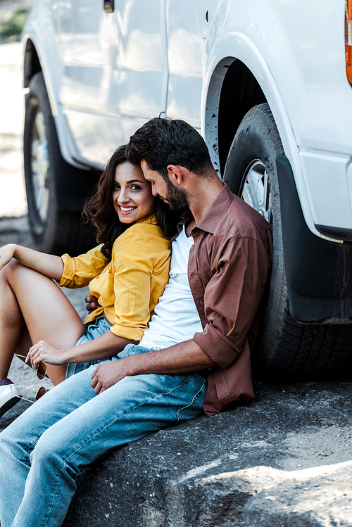 handsome and bearded man with closed eyes sitting near car with attractive woman