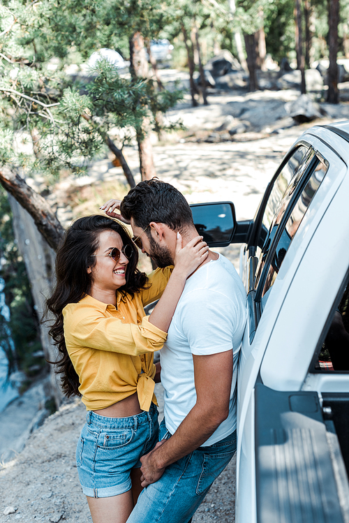 attractive girl in sunglasses hugging handsome man near car