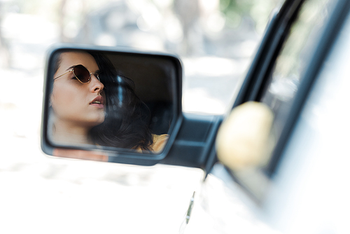 selective focus of young and attractive woman in car mirror