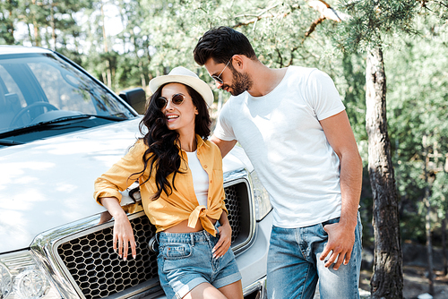 bearded man in sunglasses standing with woman in straw hat