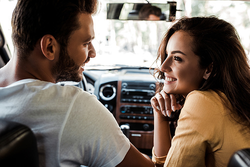 side view of happy man looking at cheerful woman in car