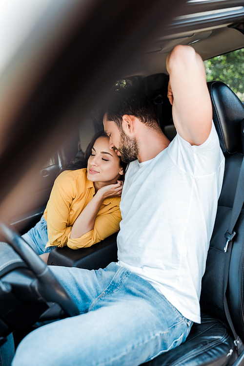 selective focus of young woman sitting near bearded man in car