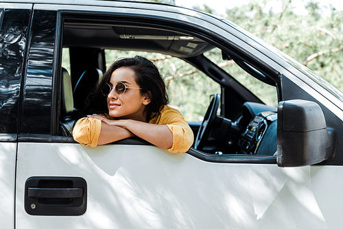 happy girl in sunglasses smiling from car window