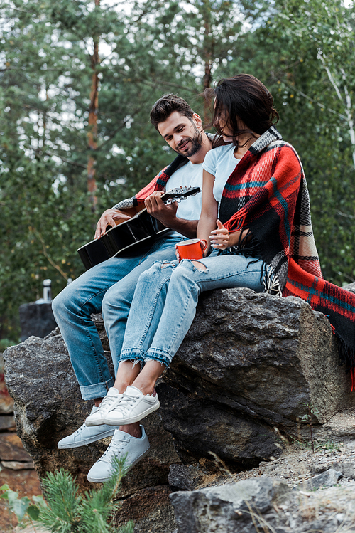 selective focus of man playing acoustic guitar near girl