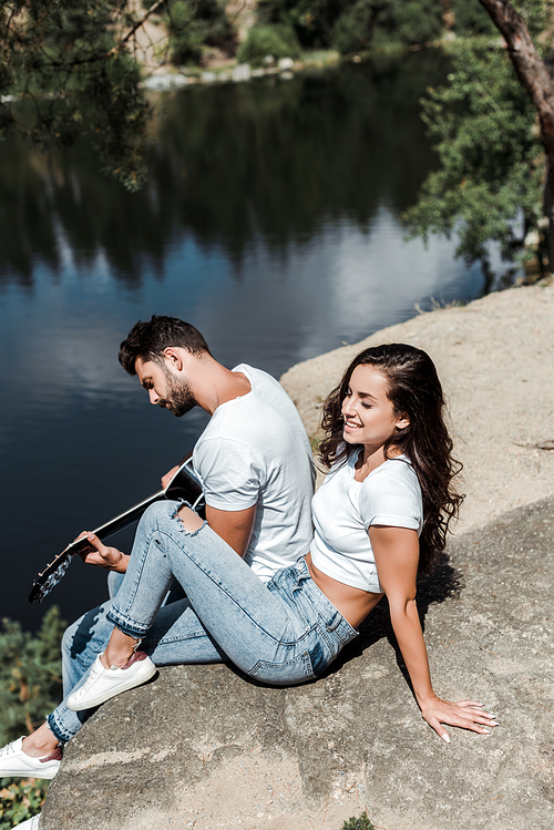 overhead view of man playing acoustic guitar near woman and lake