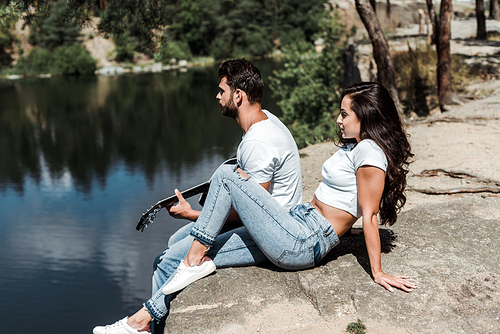 handsome man playing acoustic guitar near young woman