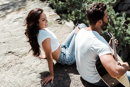 overhead view of bearded man playing acoustic guitar near cheerful woman