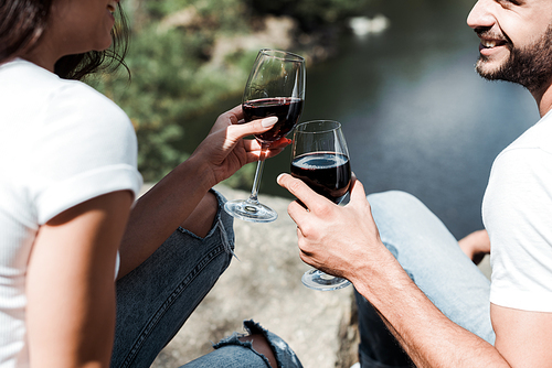 cropped view of happy bearded man and girl holding wine glasses with red wine