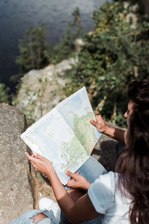 selective focus of man holding map near girl in woods