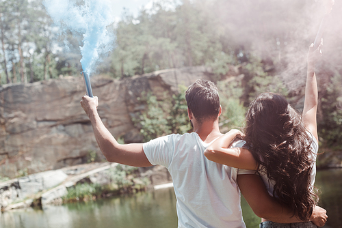 back view of man and woman holding smoke bombs