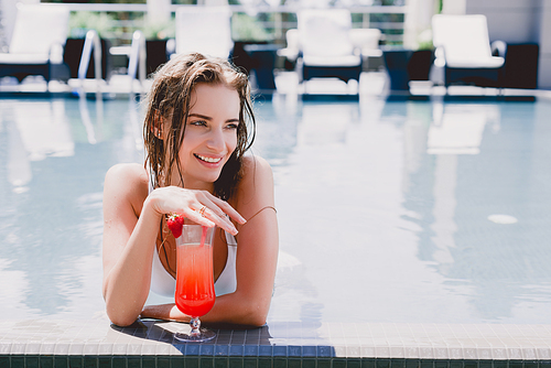 happy blonde wet woman in swimming pool with cool strawberry cocktail