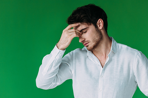 tired man in white shirt touching face with closed eyes isolated on green