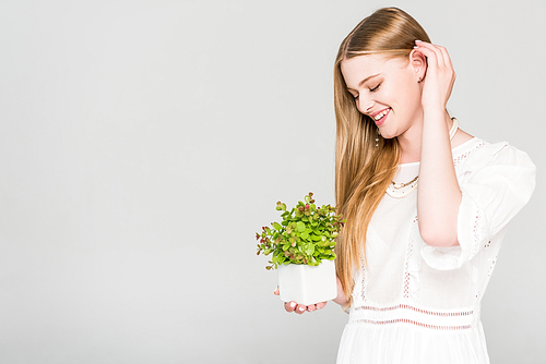 happy girl holding flowerpot with plant isolated on grey