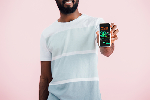 cropped view of african american man showing smartphone with marketing analysis app, isolated on pink