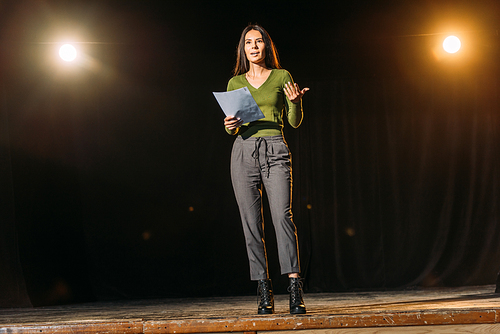 attractive young actress reading scenario on stage in theatre