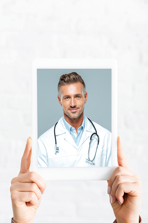 cropped view of woman holding digital tablet with doctor on online consultation, on white