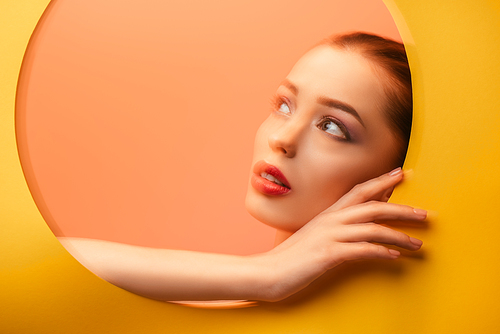 blurred image of beautiful woman in yellow paper circle hole looking away
