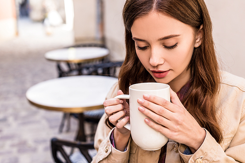 Selective focus of woman holding cup of tea in cafe