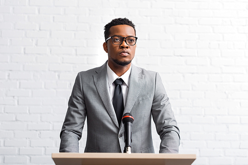 confident african american businessman having speech on tribune with microphone in conference hall