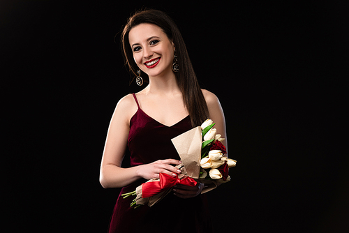 smiling woman in dress holding bouquet isolated on black