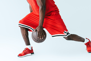 partial view of african american sportman playing basketball on grey background