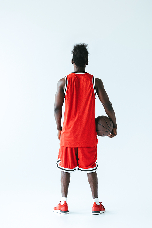 back view of african american basketball player holding ball on grey background
