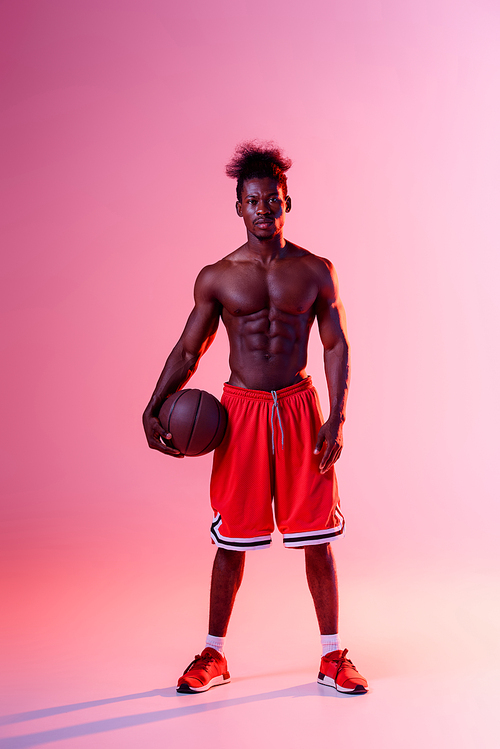 shirtless african american basketball player  on pink and purple gradient background with lighting