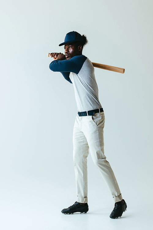 handsome african american sportsman playing baseball on grey background