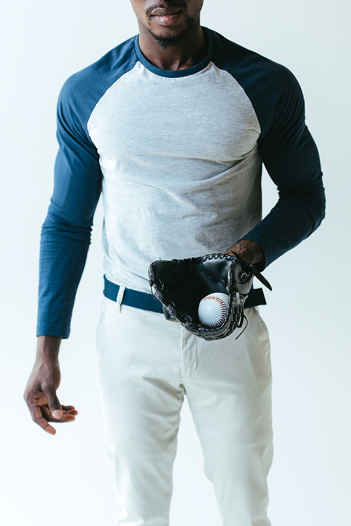 cropped view of african american sportsman with baseball glove and ball isolated on grey