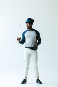 handsome african american sportsman in  glove playing with ball on grey background