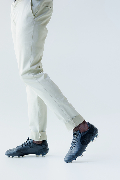 cropped view of african amrican  player in white pants and sneakers on grey background