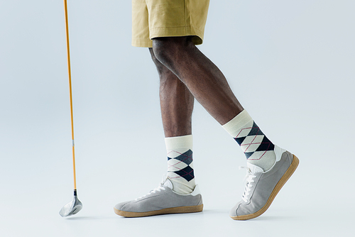 cropped view of african american sportsman holding golf club on grey background