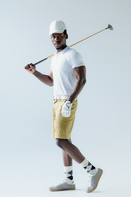 confident african american golf player  on grey background