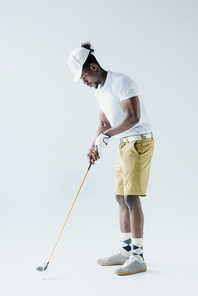 handsome african american sportsman playing golf on grey background