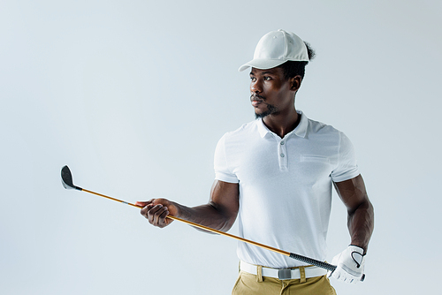 serious african american sportsman holding golf club isolated on grey