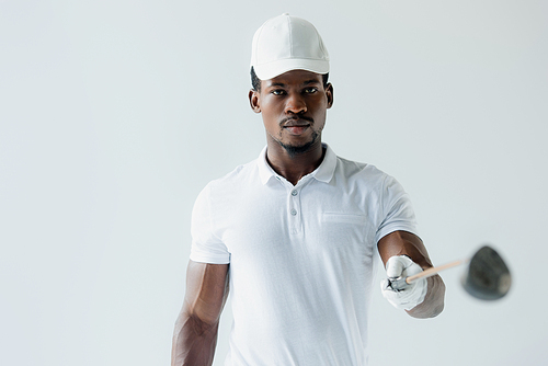 confident african american sportsman presenting golf club isolated on grey