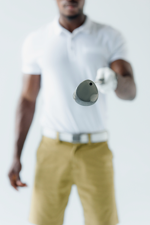 selective focus of african american sportsman showing golf club isolated on grey