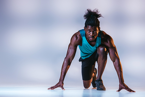 african american sportsman standing in start position and  on grey background with lighting