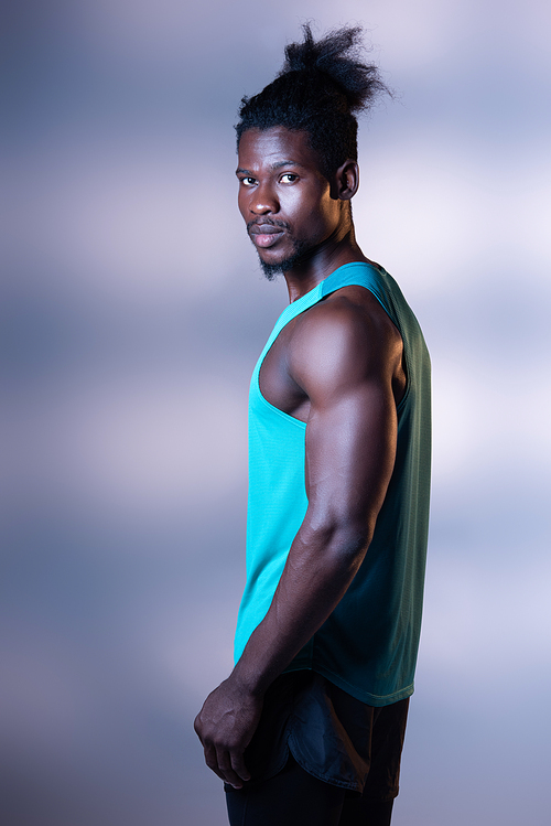 handsome, muscular african american sportsman posing at camera on grey background with lighting