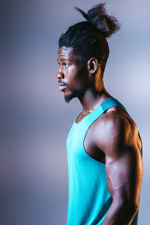young, hadsome african american sportsman looking away on grey background with lighting