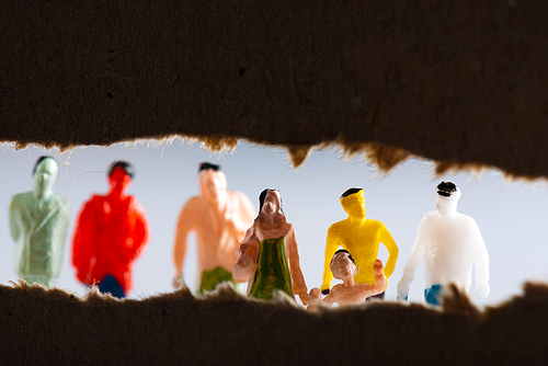 Selective focus of cardboard with hole and people figures isolated on grey