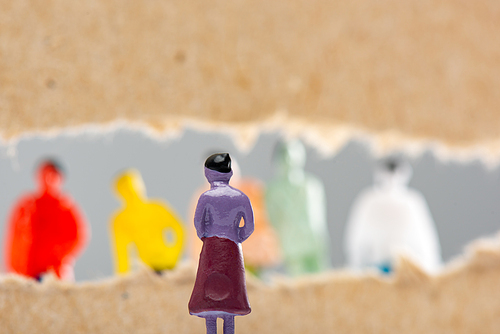 Selective focus of toy near hole in cardboard with people figures isolated on grey, concept of social rights