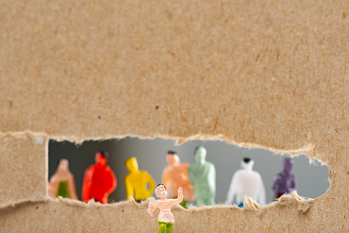 Close up view of toy near cardboard with hole and silhouettes of people figures isolated on grey, concept of social rights
