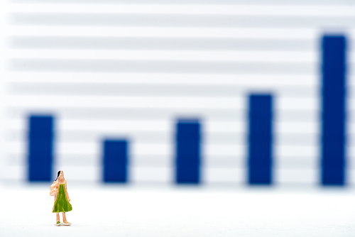 Selective focus of doll on white surface with charts at background, concept of equality