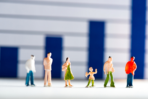 Selective focus of people figures on white surface with analytics graphs at background, concept of equality