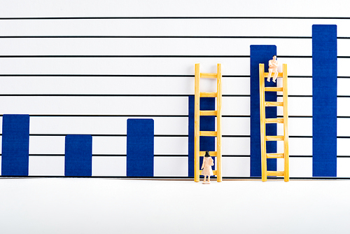 People figures with ladders near charts on white surface, equality concept