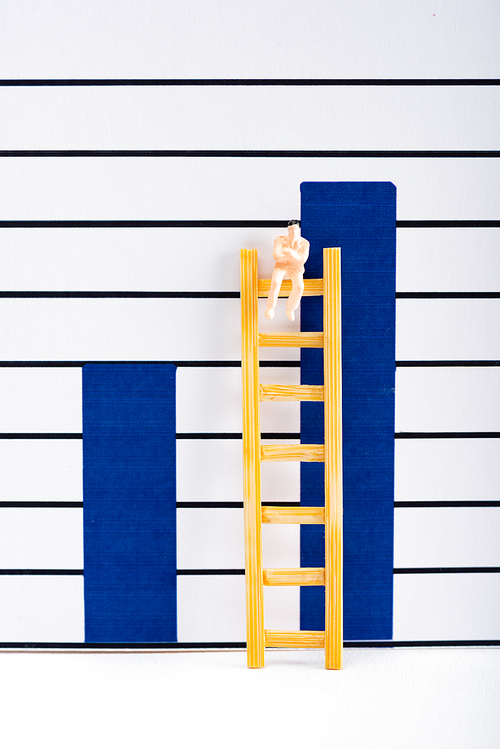 Doll on ladder on white surface near graphs at background, equality concept