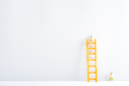 Two people figures with ladder on white surface on grey background, concept of equality rights