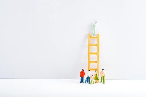 People figures near ladder with toy on white surface on grey background, concept of equality rights