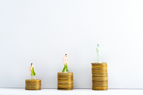 Row of people figures on coins on white surface on grey background, concept of financial equality